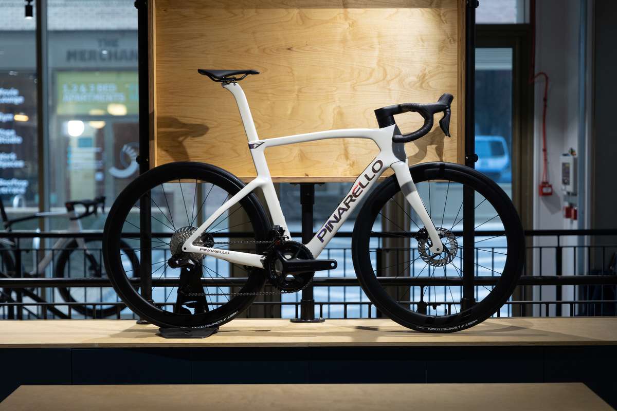 A white Pinarello road bike on a wooden plinth in the PowerWatts retail space